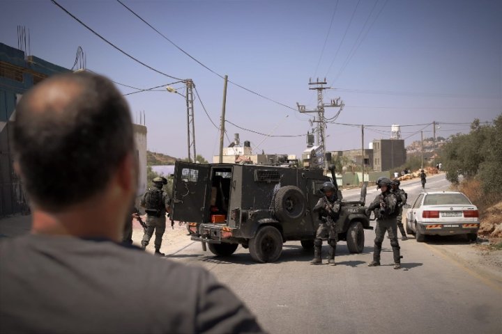 Unitats de l'exèrcit d'Iisrael arriben als voltants de l'habitatge. Enfront, un veí tractant d'apropar-se per defensar la casa. Foto: Caterina Albert