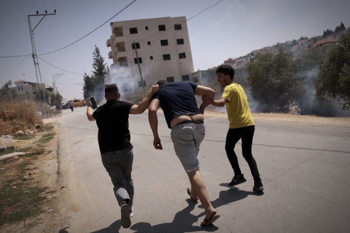 Dos palestins intenten desplaçar-ne un altre lluny dels soldats en busca d'un cotxer per poder anar a l'hospital després d'haver rebut un impacte de bala de goma al costat de l'ull. Foto: Caterina Albert